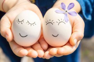 hands holding decorated easter eggs with happy faces