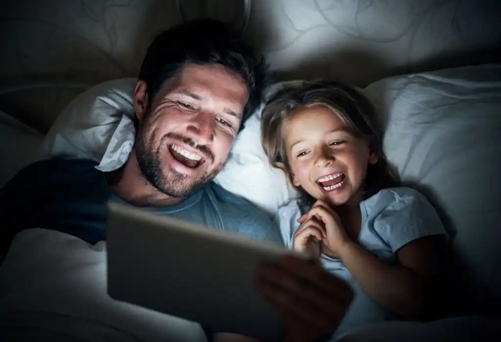 dad reading bedtime story to daughter in bed