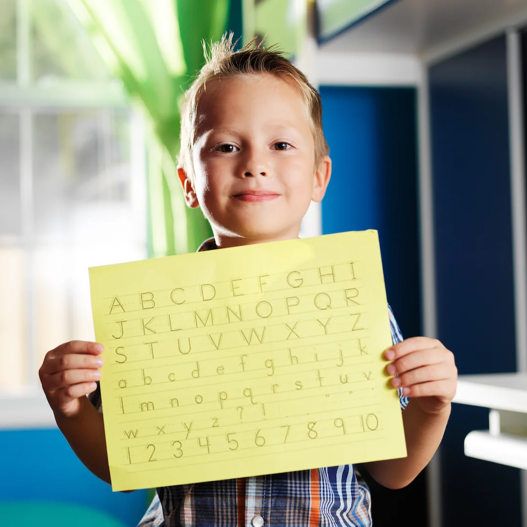 little boy holding completed homework square
