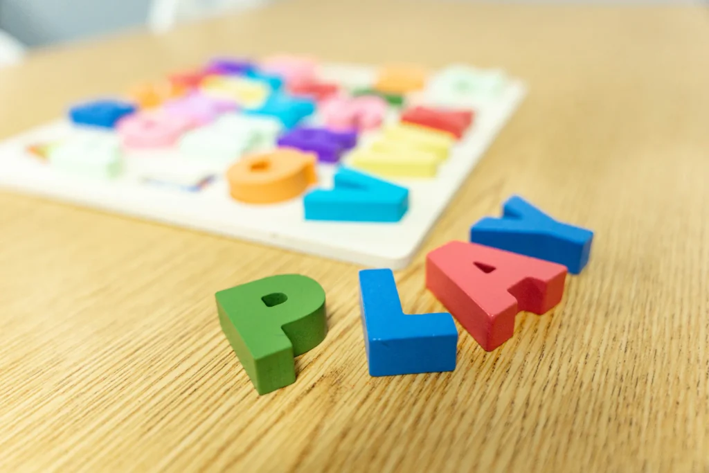 Alphabet puzzle letters spelling PLAY on a classroom table