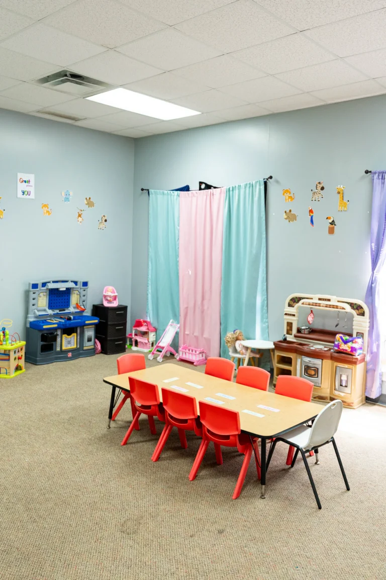 Bright toddler classroom with child-size tables and play kitchen