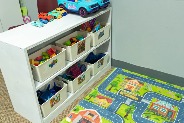 Toy bins and road play rug in a preschool classroom